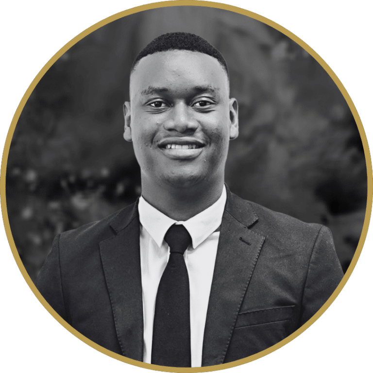 Black and white portrait of a smiling young Black man in a suit and tie, framed in a gold-bordered circle.